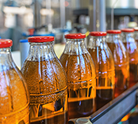 Filled beverage bottles travelling on a production line during the packaging process.