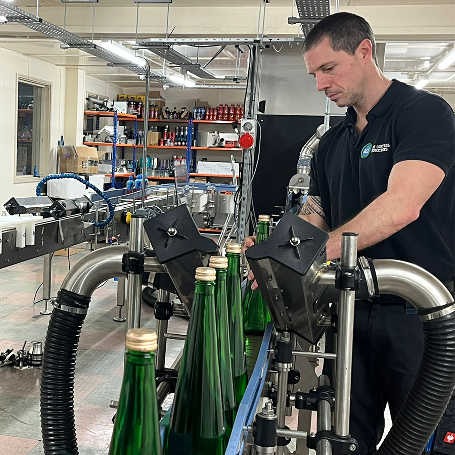 Engineer testing a Hyroic bottle drying system on a conveyor line in an in-house testing facility.